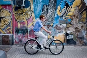 hombre en bicileta frente a un grafiti tonos pasteles fotografia callejera rosario