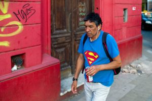 hombre con malla de superman camina frente a pared roja fotografia callejera rosario