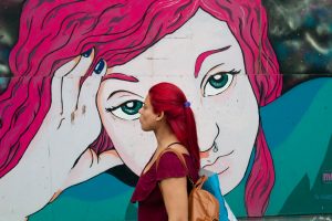 mujer con pelos rojos paras frente a un grafiti rojo fotografia callejera rosario