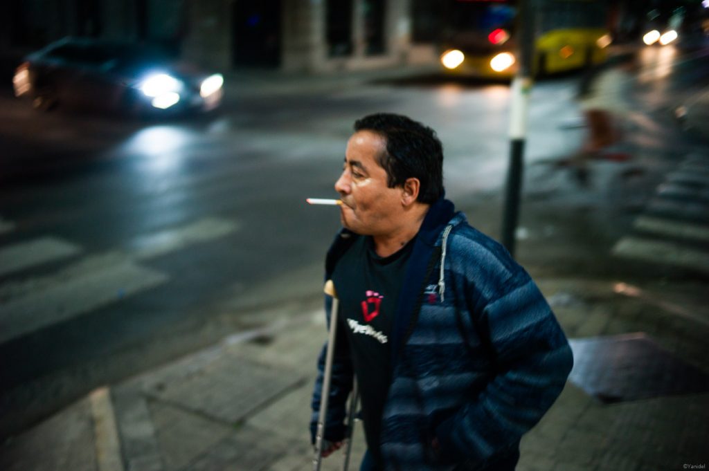 man smokes downtown rosario, with looks of narco city, that is street photography in Argentina.